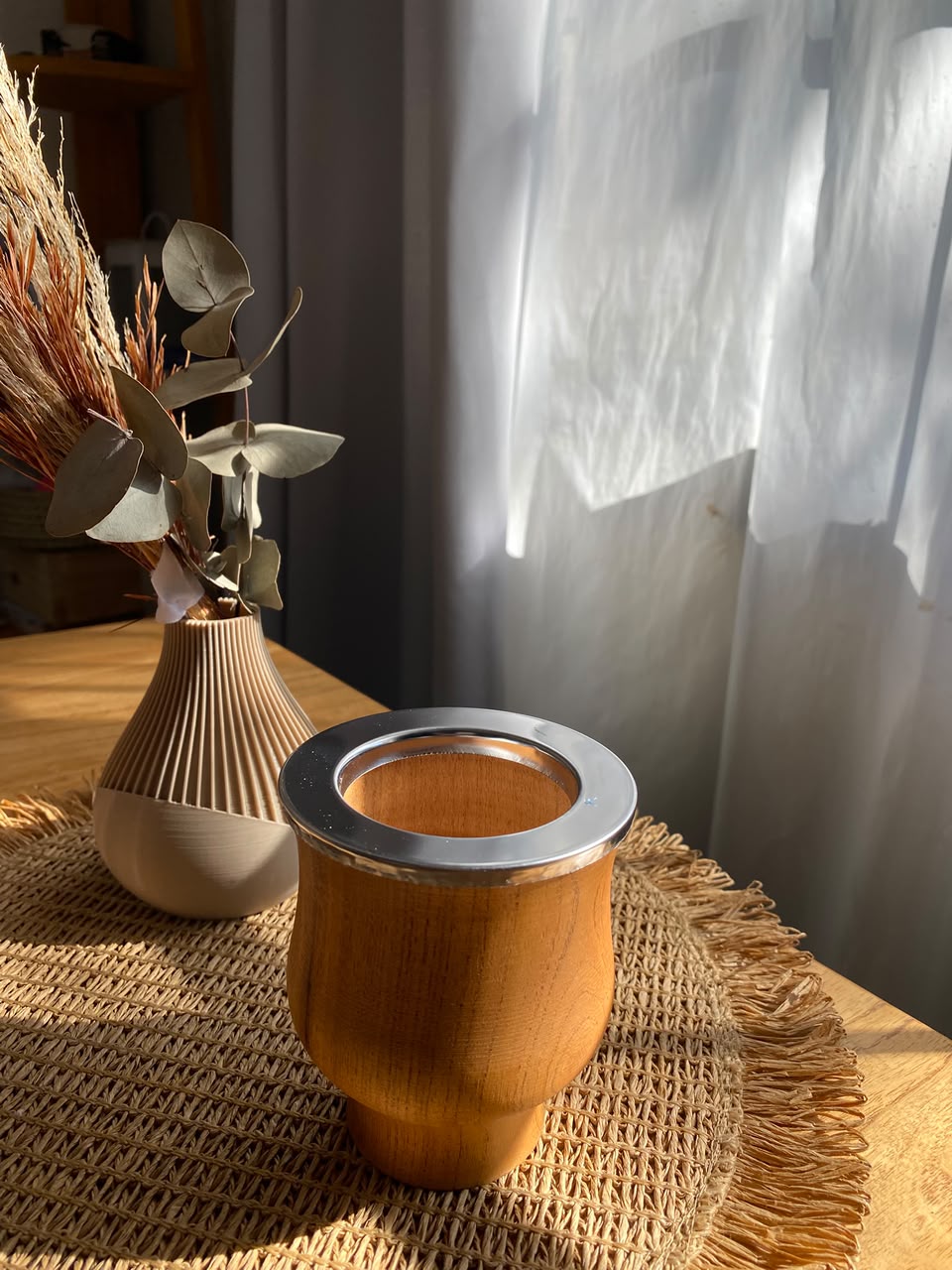 Mate de madera con virola metálica de Matecito, sobre una mesa iluminada por el sol